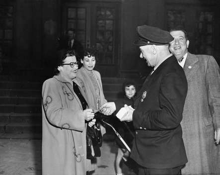 William Comerford, driver for Camden's fire chief, passing out circulars in front of Alfred Cramer School, 1949