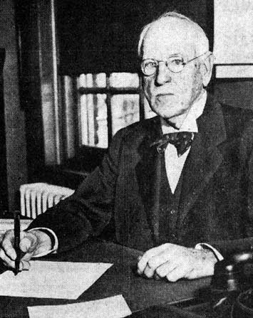 Frank T. Lloyd seated at a desk, writing, 1938