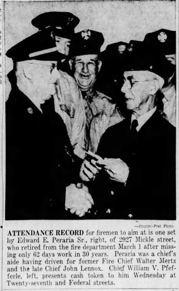 Two uniformed Camden firemen shaking hands as one presents a cash token, with other firemen smiling behind them