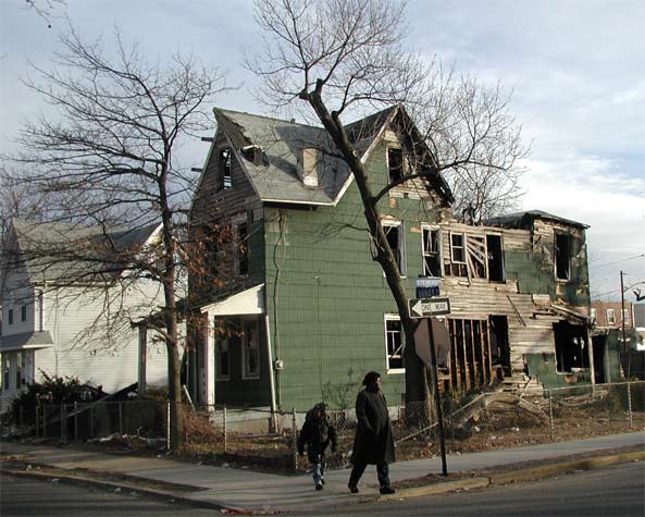 Burned green corner house with street sign
